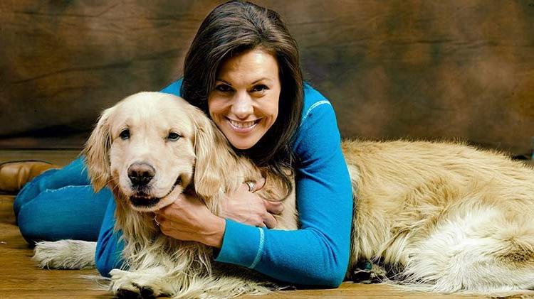 Woman lying on the floor hugging her golden retriever.