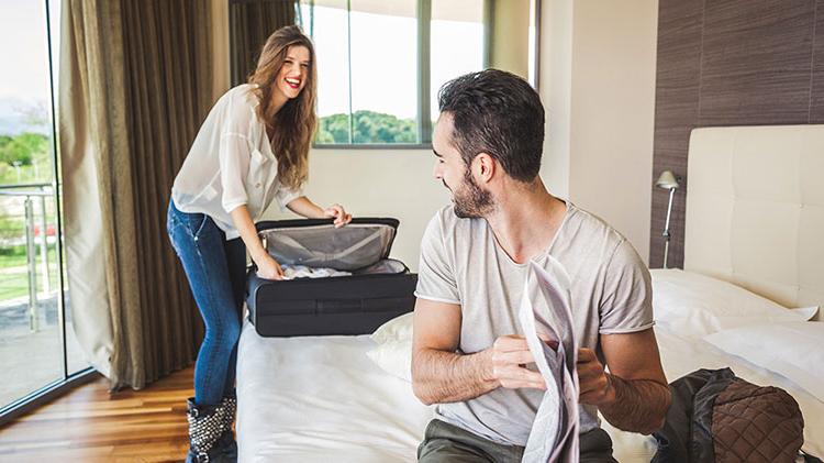 A couple unpack inside their hotel room.